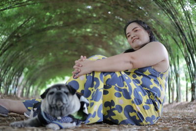 Portrait of woman with pug sitting on land