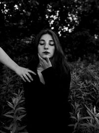 Young woman with eyes closed standing amidst plants