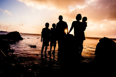 Silhouette people on beach at sunset