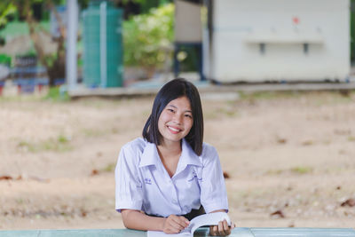 Portrait of young woman sitting on field