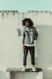 Full length portrait of young man standing against wall