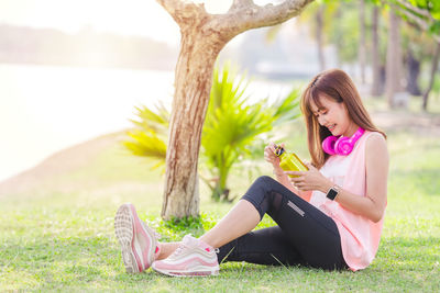 Young woman using phone while sitting outdoors