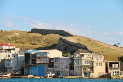 Houses by sea against sky