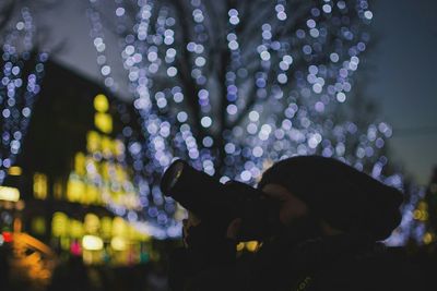 Close-up of man photographing at night during christmas