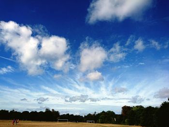 Trees on landscape against cloudy sky