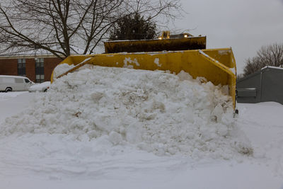 Snow covered street by building during winter