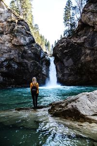 Man standing on rock against waterfall