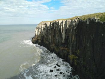 Scenic view of mountain cliff and sea against sky