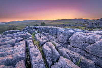 Rock formations on landscape against sky during sunset