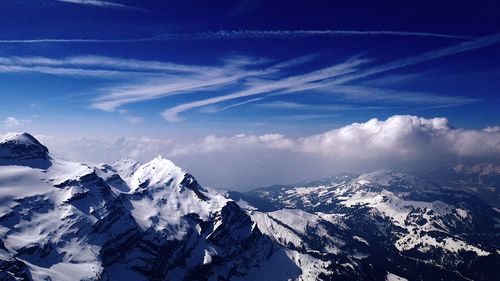 Scenic view of snow covered mountains against blue sky