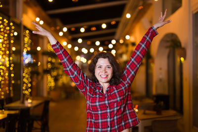 Portrait of smiling woman against illuminated lighting