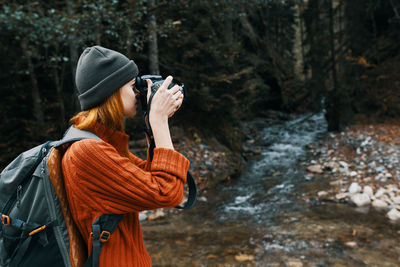 Rear view of woman photographing in forest