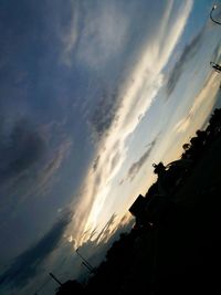 Low angle view of silhouette trees against cloudy sky