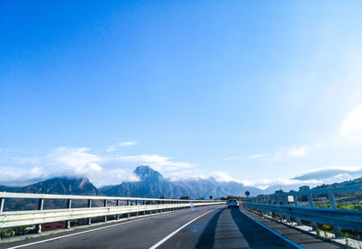 Highway by suspension bridge against blue sky