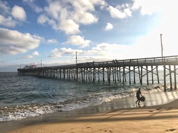 Man walking on beach by sea against sky