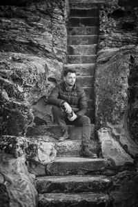 Man sitting on staircase against wall