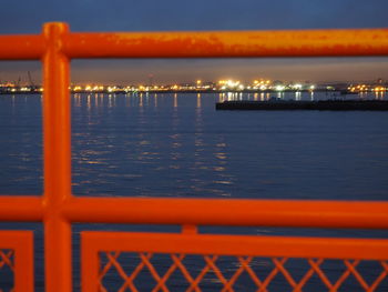 Close-up of cityscape by sea against sky during sunset