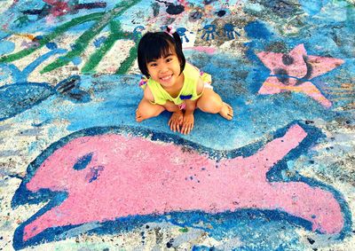 High angle portrait of happy smiling woman against graffiti