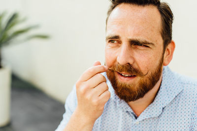 Bearded caucasian man with freckles touching his moustache