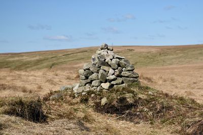 Stone wall on field against sky