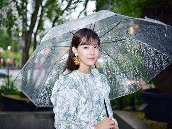 Portrait of woman with umbrella standing in rain during rainy season