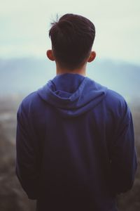 Rear view of boy standing against sky
