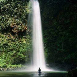 Woman swimming in river against waterfall