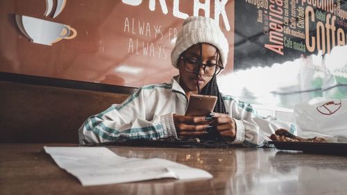 Young woman using smart phone in restaurant