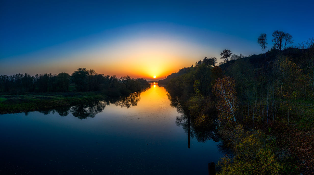 SCENIC VIEW OF LAKE AGAINST BLUE SKY AT SUNSET