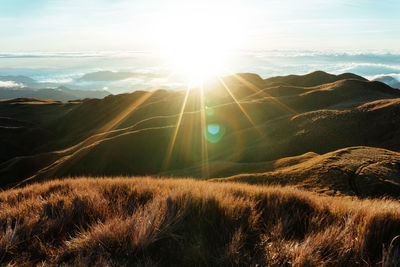 Sunlight streaming through clouds over landscape