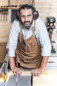 Portrait of carpenter listening music while working in workshop