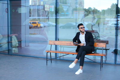 Businessman holding digital tablet sitting on bench