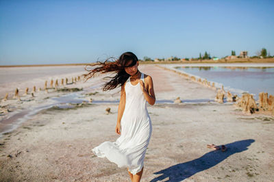 Woman with long dark hair in windy beach of pink sea