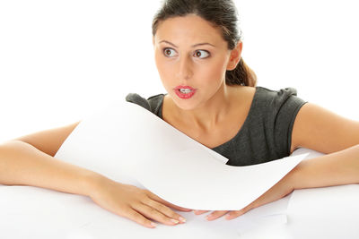 Portrait of young woman sitting against white background