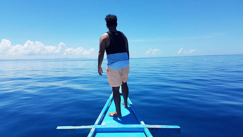 Rear view of man looking at sea against sky