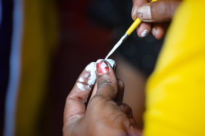 Cropped hand of woman applying nail