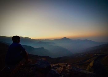 Rear view of a man on landscape at sunset