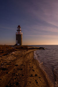 Lighthouse by sea against sky