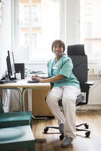 Full length of senior woman sitting on table