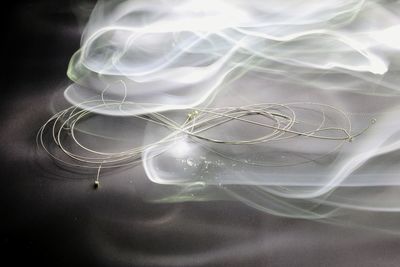 Close-up of in-ear headphones on table against light painting