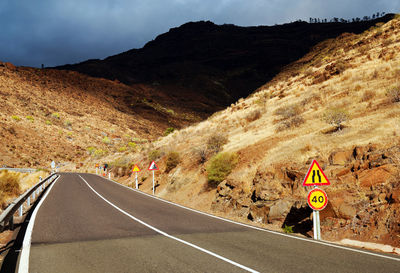 Road amidst mountains against cloudy sky