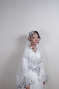 Portrait of bride standing against wall