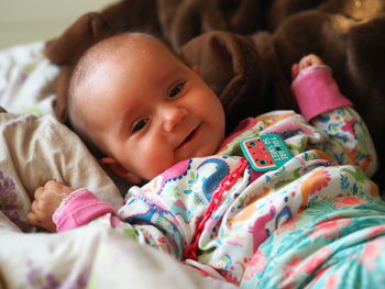 Portrait of cute baby girl lying on bed