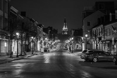 Cars on road by illuminated buildings in city at night