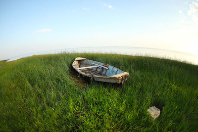 Boat moored on grassy field against sky