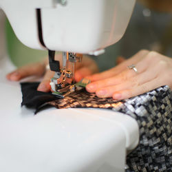 Cropped hands of woman sewing clothes on machine