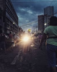 Rear view of people walking on illuminated street at dusk