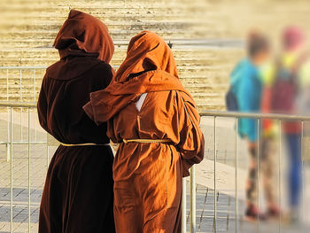 Rear view of people standing against the water