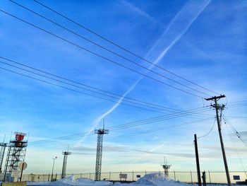 Low angle view of electricity pylon against blue sky