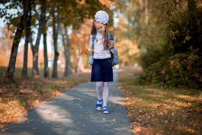 Full length of girl walking on footpath in park during autumn